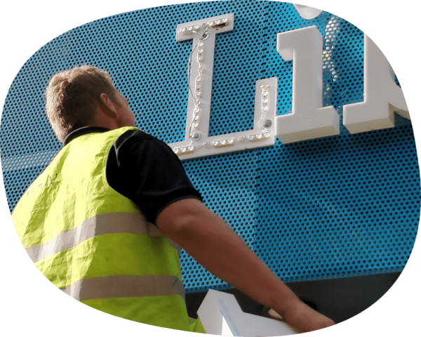man in hi-vis looking at plastic sign.