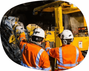 two miners talking in front of machinery.