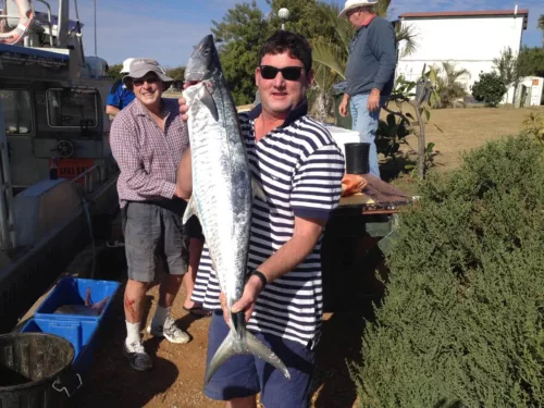a man holding a fish while standing next to another man.